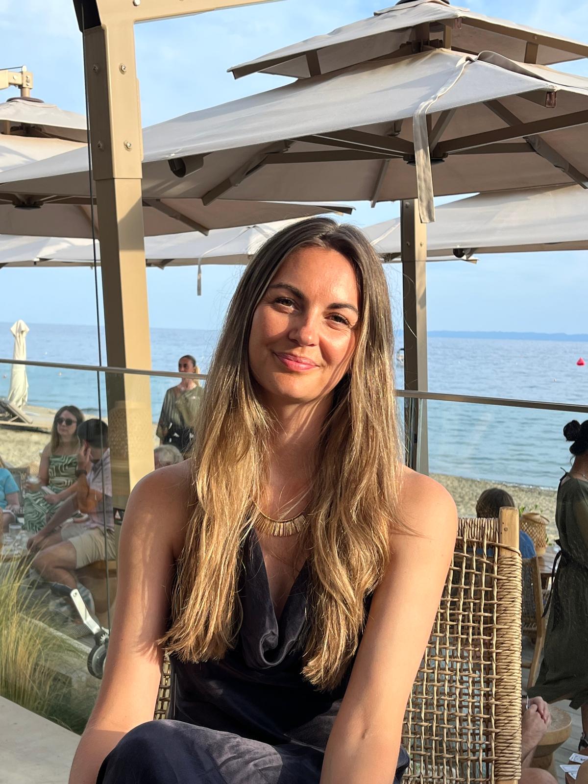 Charlotte Sapak smiling, seated by the sea